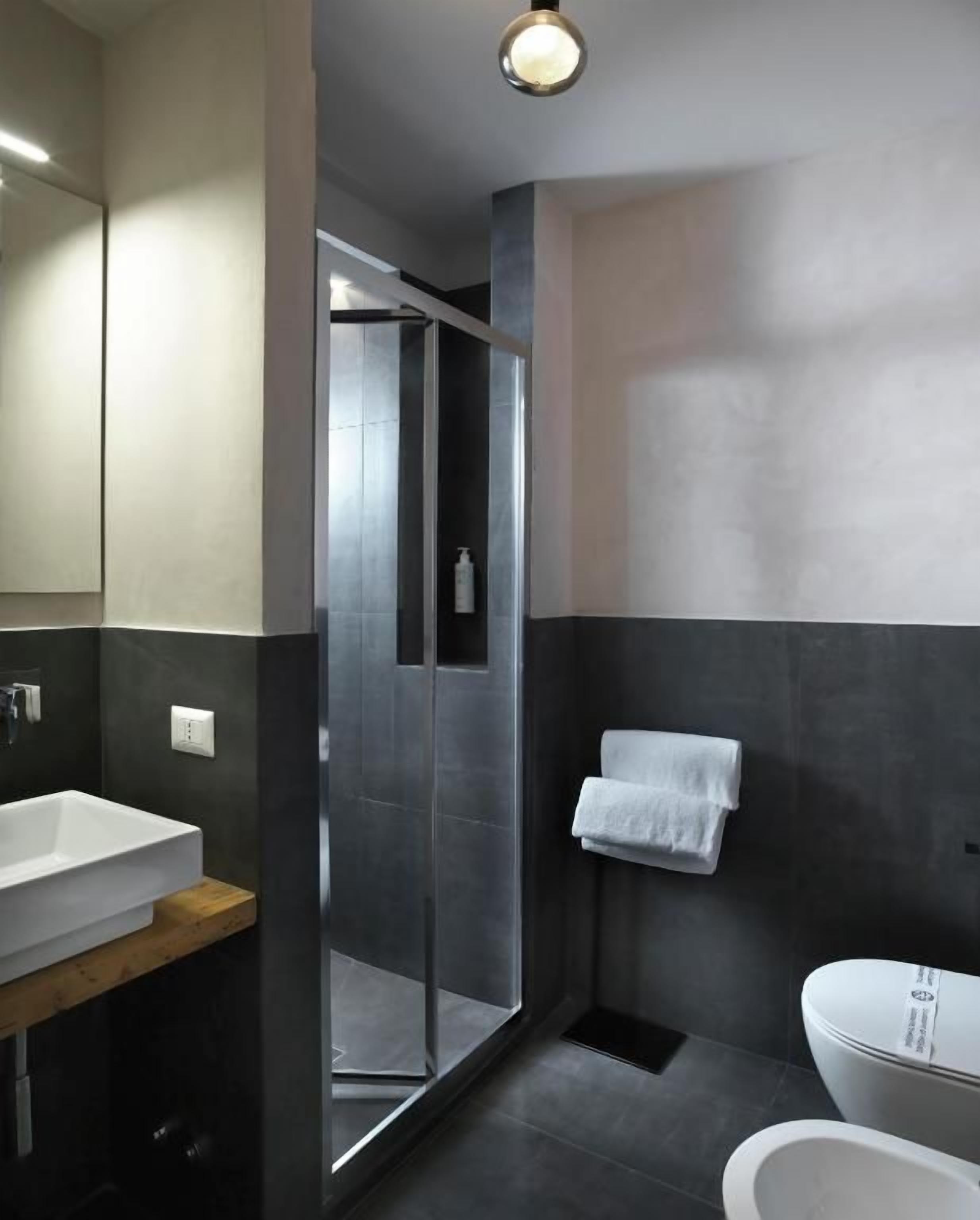 Un baño moderno con cabina de ducha de vidrio, un lavamanos blanco y un inodoro.