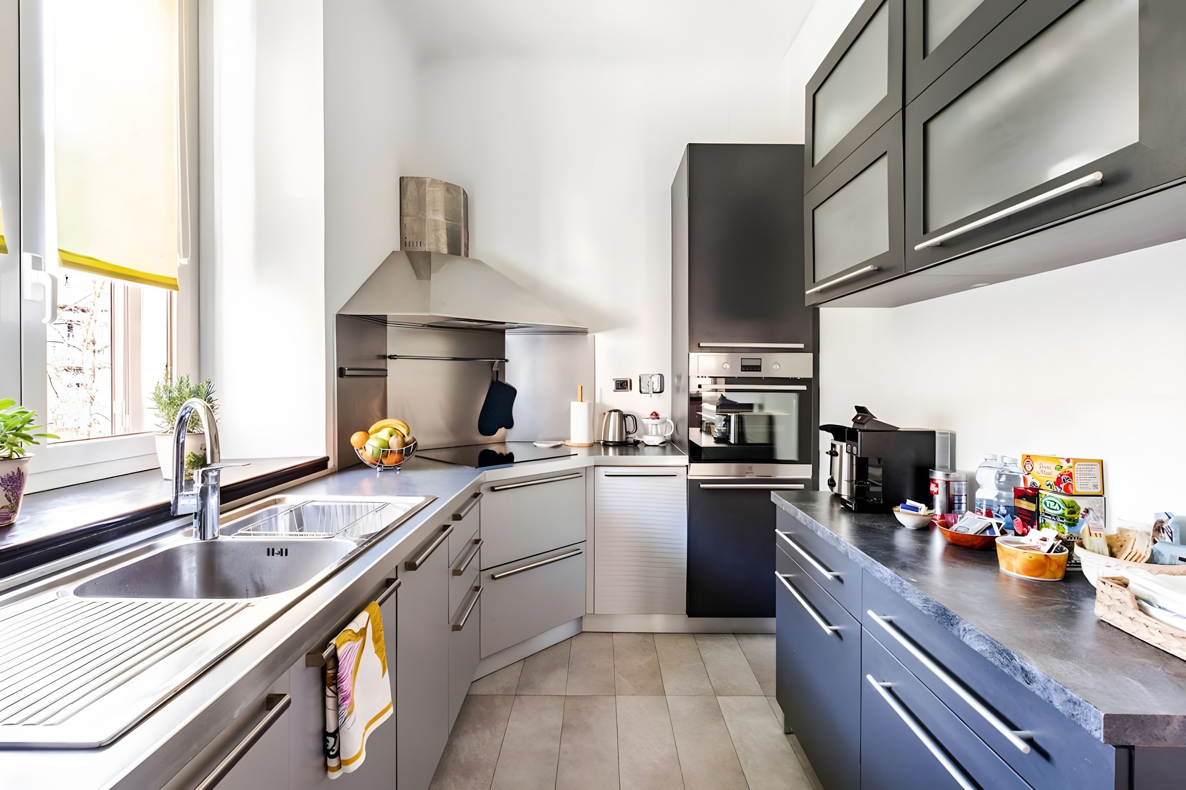 A modern kitchen with stainless steel appliances, a built-in oven, and a large window providing natural light.