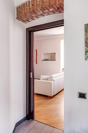 Un espacio interior con piso de madera, un sofá blanco y una pared de ladrillo.