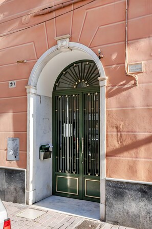 Una entrada de edificio con un portón verde, un buzón y un cartel con un número.
