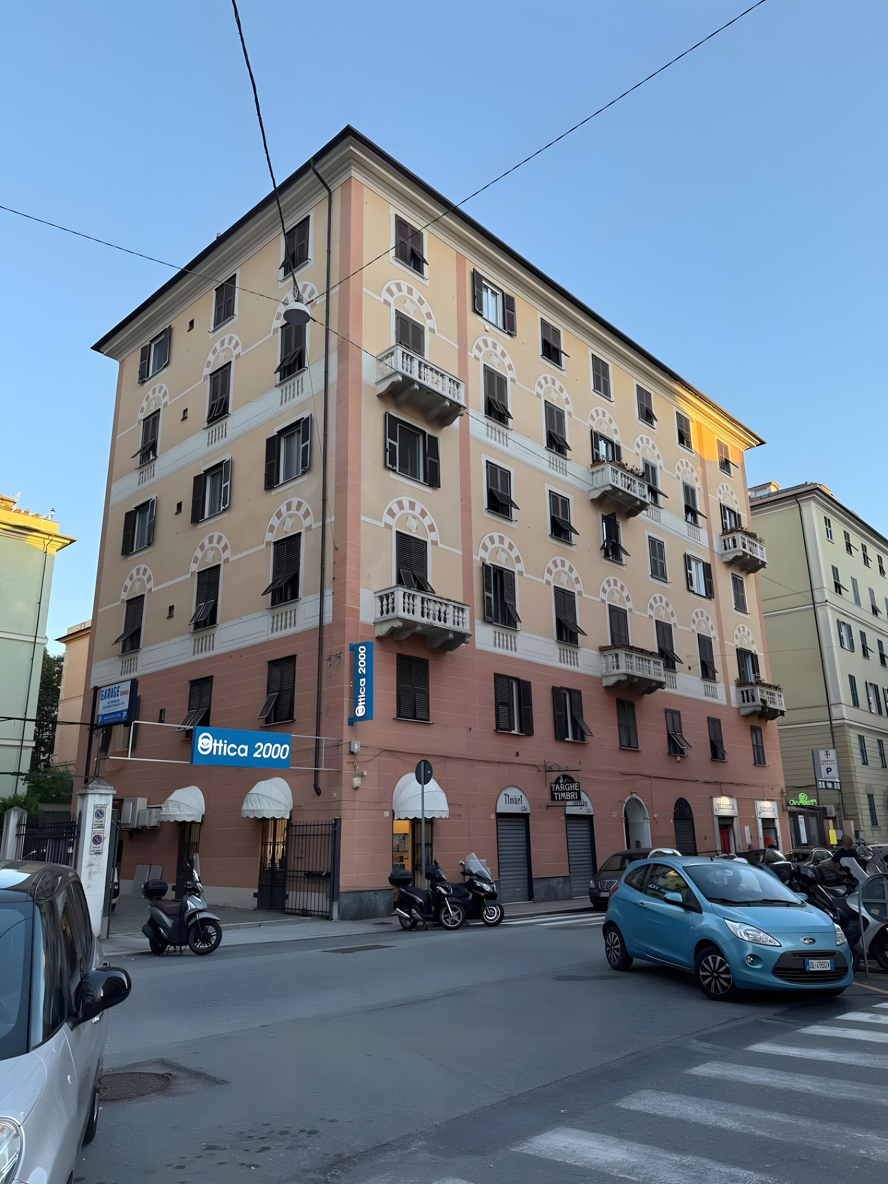 Un immeuble à plusieurs étages doté de balcons, une enseigne indiquant « Etica 2000 », et des véhicules stationnés dans la rue.