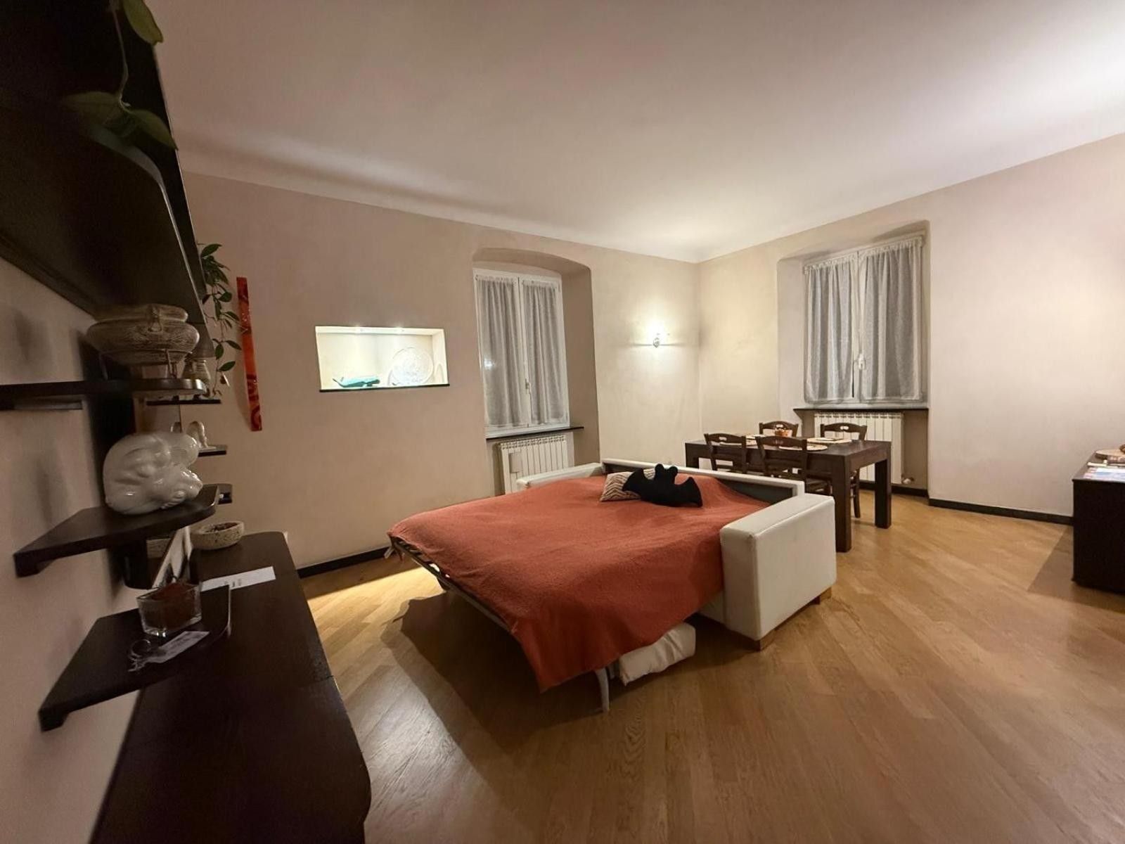 Ein Schlafzimmer mit einem Bett, einem Nachttisch, einer Lampe und einem kleinen Tisch mit einer Vase.