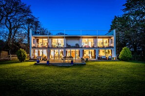 Una casa de dos pisos con un balcón grande y varias ventanas.