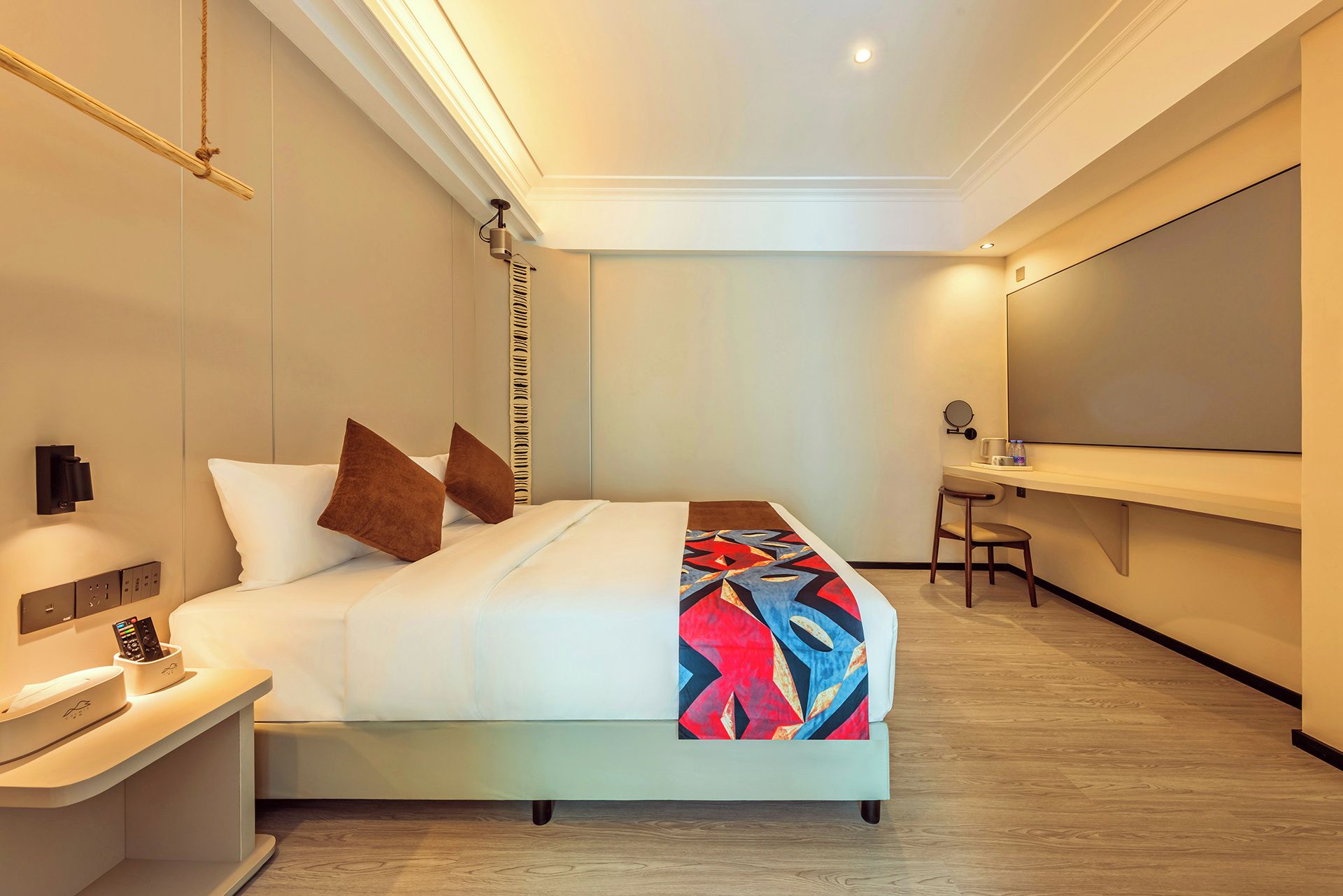 Quarto de hotel com cama, mesa de cabeceira e escrivaninha com cadeira.