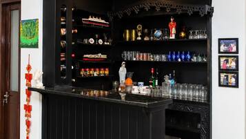 A bar area with shelves of bottles and glasses, a decorative statue, and a red ornament on the wall.
