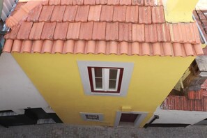 Ein gelbes Gebäude mit rotem Ziegeldach und Fensterrahmen in Weiß.