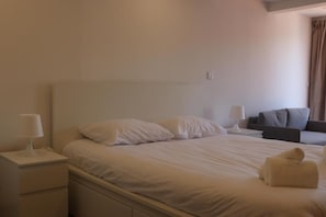 Ein Hotelzimmer mit einem Bett, einem Nachttisch, einer Lampe und einer Sitzecke mit einem Sofa.