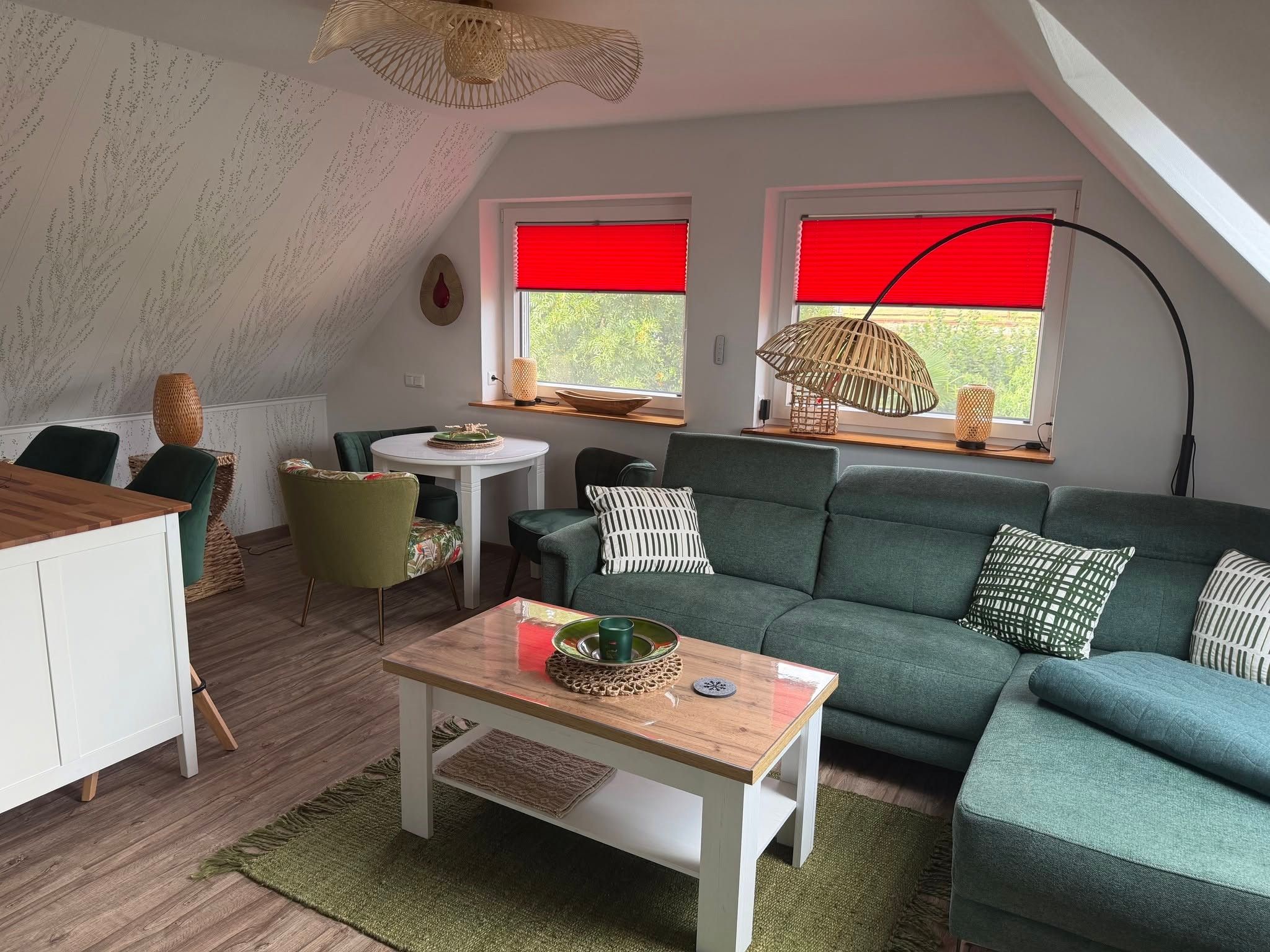Ein gemütliches Wohnzimmer mit einem grünen Sofa, einem Holztisch und einem Essbereich mit Tisch und Stühlen.