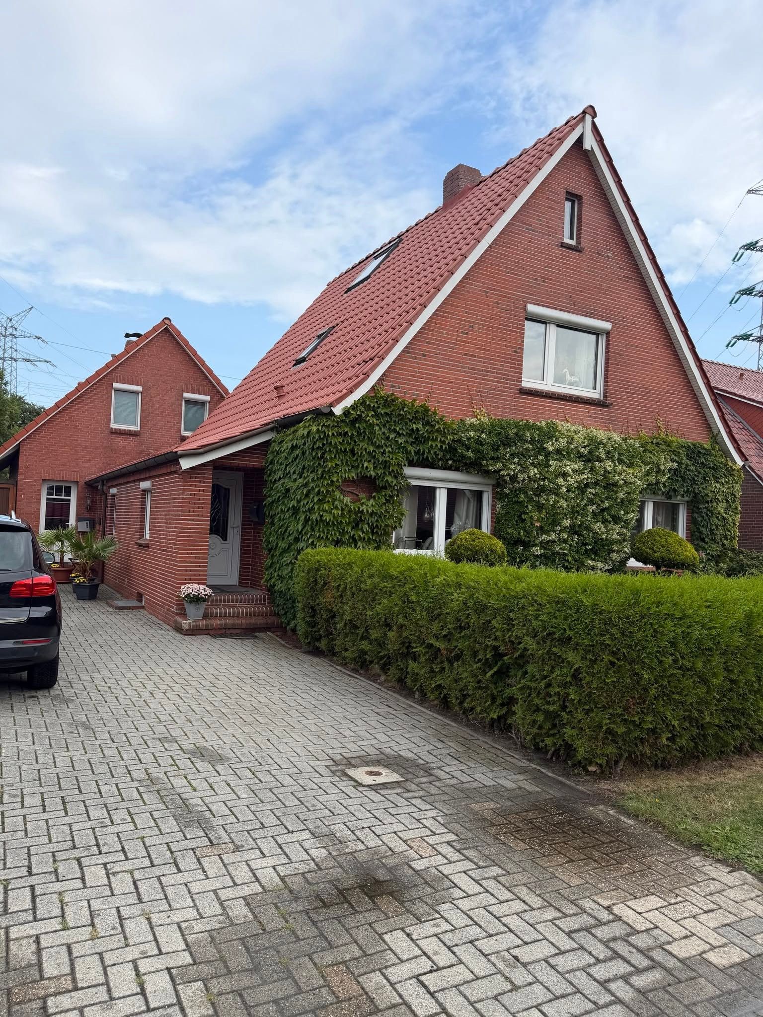 Ein Wohngebäude mit roter Backsteinfassade, geneigtem Dach und befestigter Auffahrt.