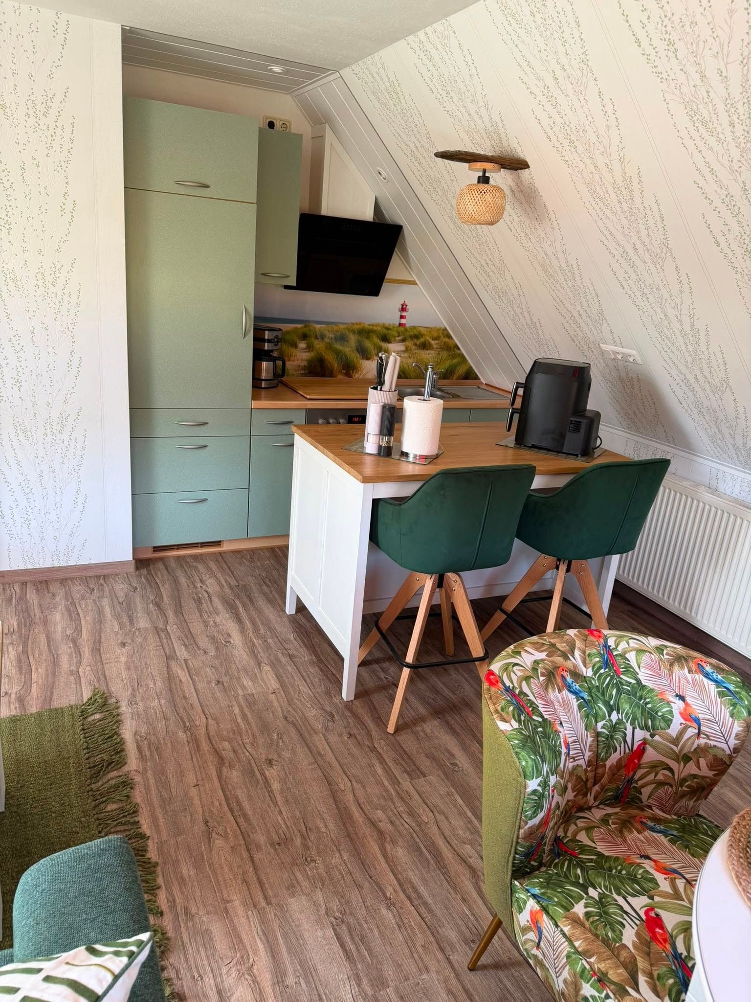 Eine kompakte Küche mit Essbereich, inklusive Tisch und Stühlen, einer Kaffeemaschine und einem Fernseher über der Arbeitsfläche.