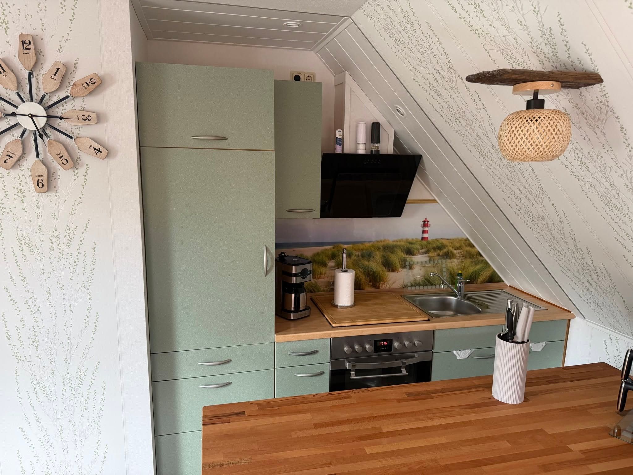 Eine kleine Küche mit einem grünen Schrank, einer Kaffeemaschine und einem Spülbecken.
