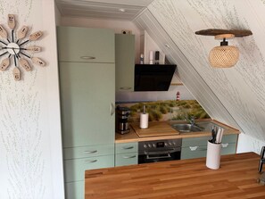 A compact kitchen with a green cabinet, a coffee machine, and a sink. - Apartment 'Haus Ulrike' with Wi-Fi (Norden)