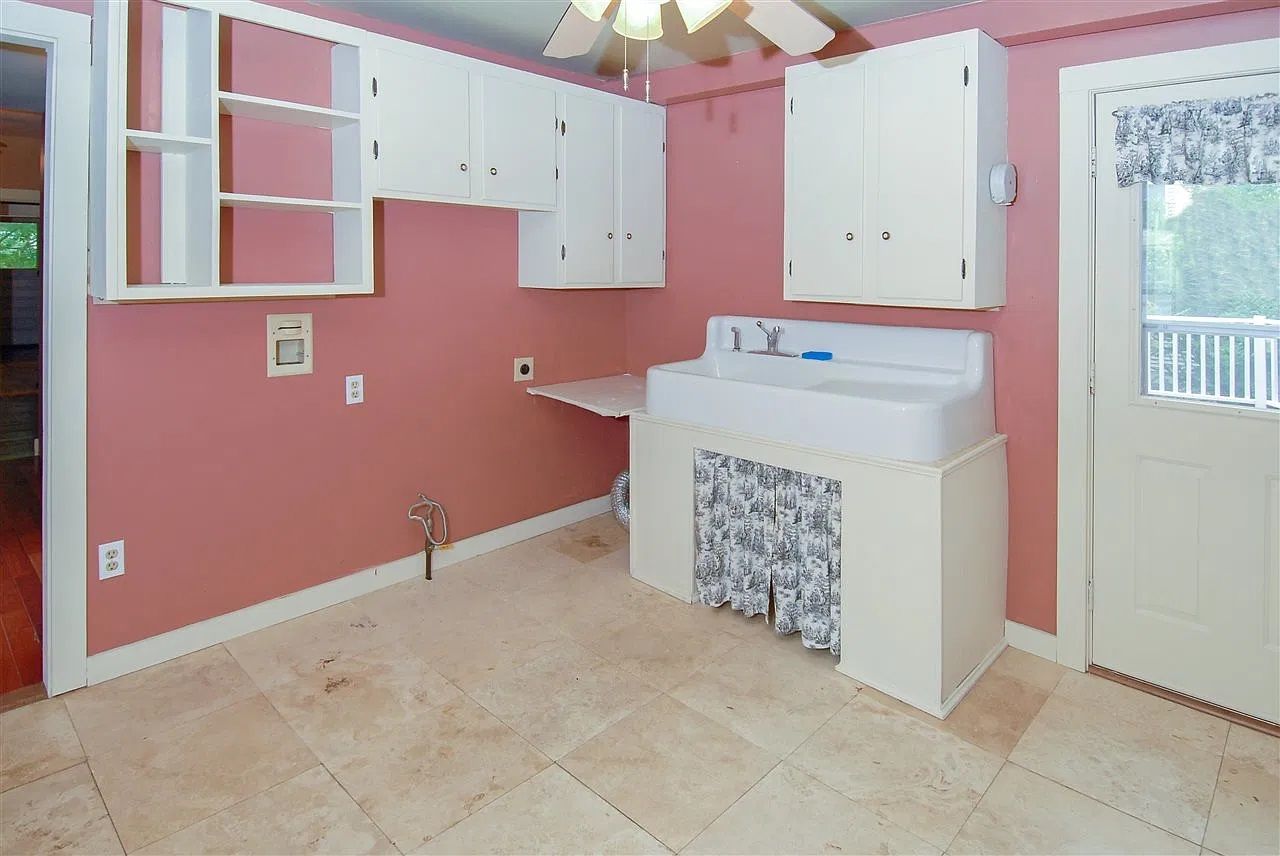 A room with pink walls, a white sink, and cabinets.
