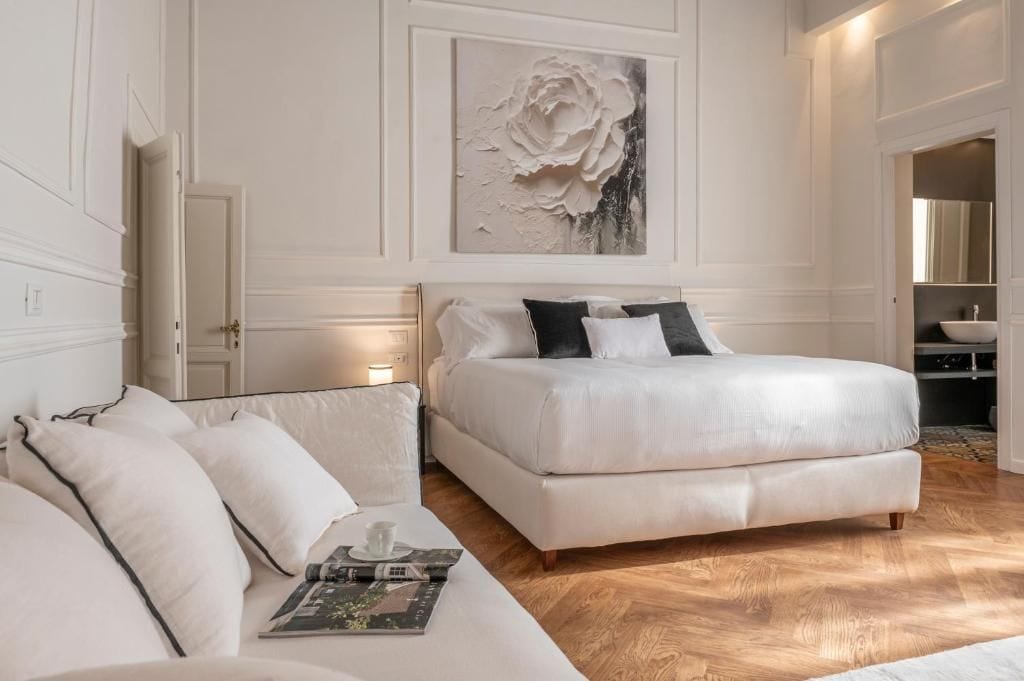 A bedroom with a large bed, a sofa, and a painting on the wall.