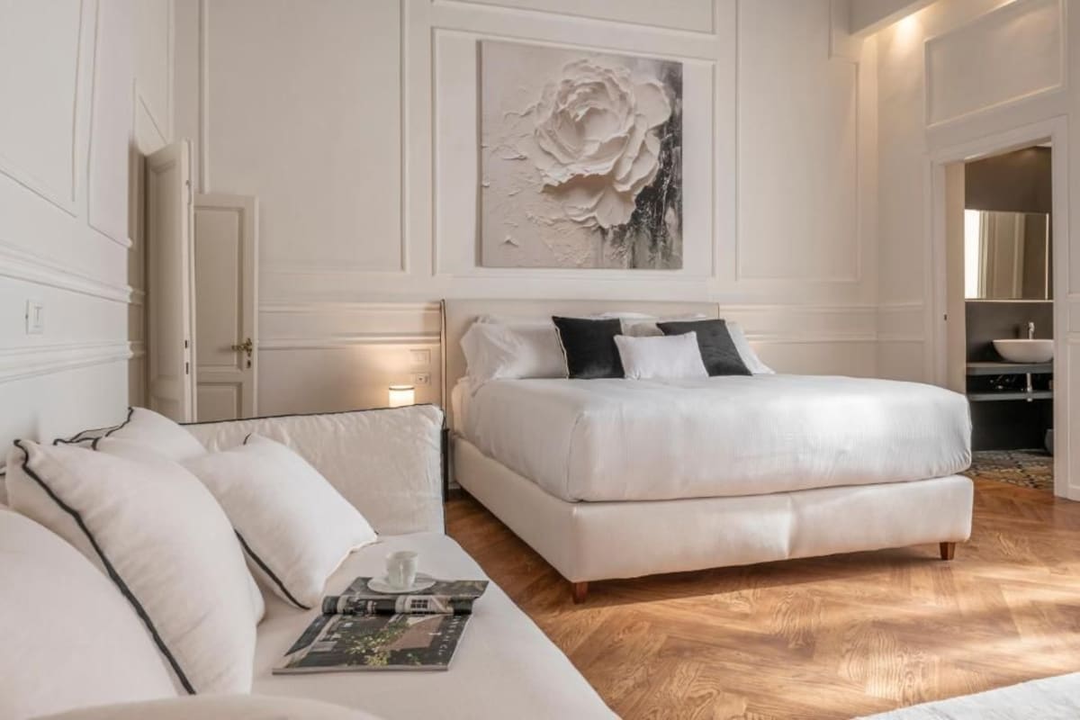 Een slaapkamer met een groot bed, een bank en een schilderij aan de muur.