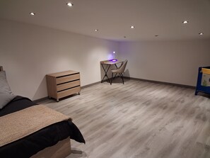 Een slaapkamer met een bed, een kaptafel, een bureau met stoel en een klein boekenrek.