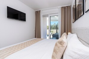 Une chambre d’hôtel avec un lit, un téléviseur à écran plat fixé au mur et une vue sur l’extérieur grâce à une porte vitrée.