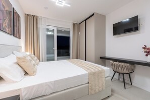 Une chambre d’hôtel équipée d’un lit, d’un bureau, d’une chaise, d’une télévision et offrant une vue sur l’extérieur.