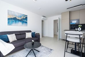 Ein modernes Wohnzimmer mit einem grauen Sofa, einem runden Couchtisch und einem Bild an der Wand.