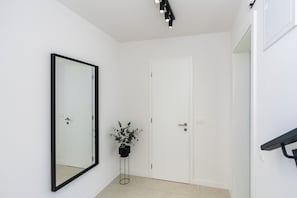 Ein Flur mit einer weißen Tür, einem großen Spiegel und einem Blumentopf.
