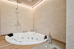 Un baño moderno con una bañera independiente, un cabezal de ducha de mano y una botella de champán.