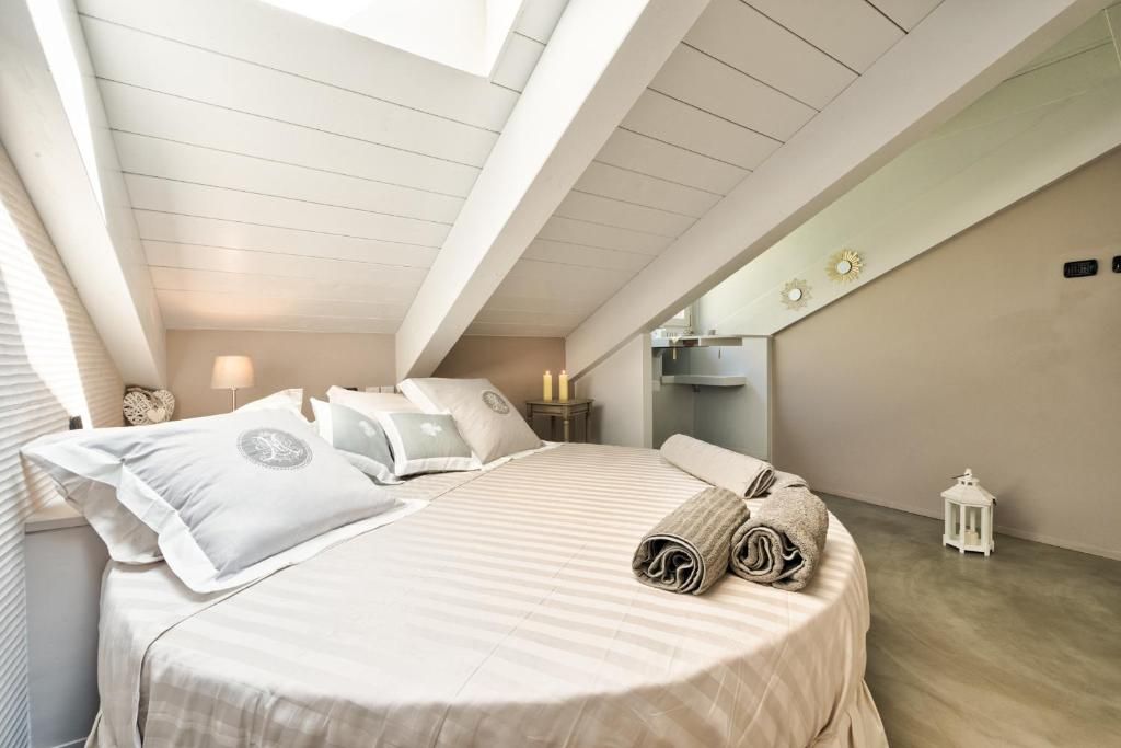 A bedroom with a skylight, a bed with pillows and a rolled towel, a nightstand with a lamp, and a small lantern.