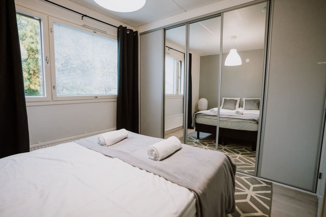 Una habitación de hotel con cama, armario y ventana con cortinas.