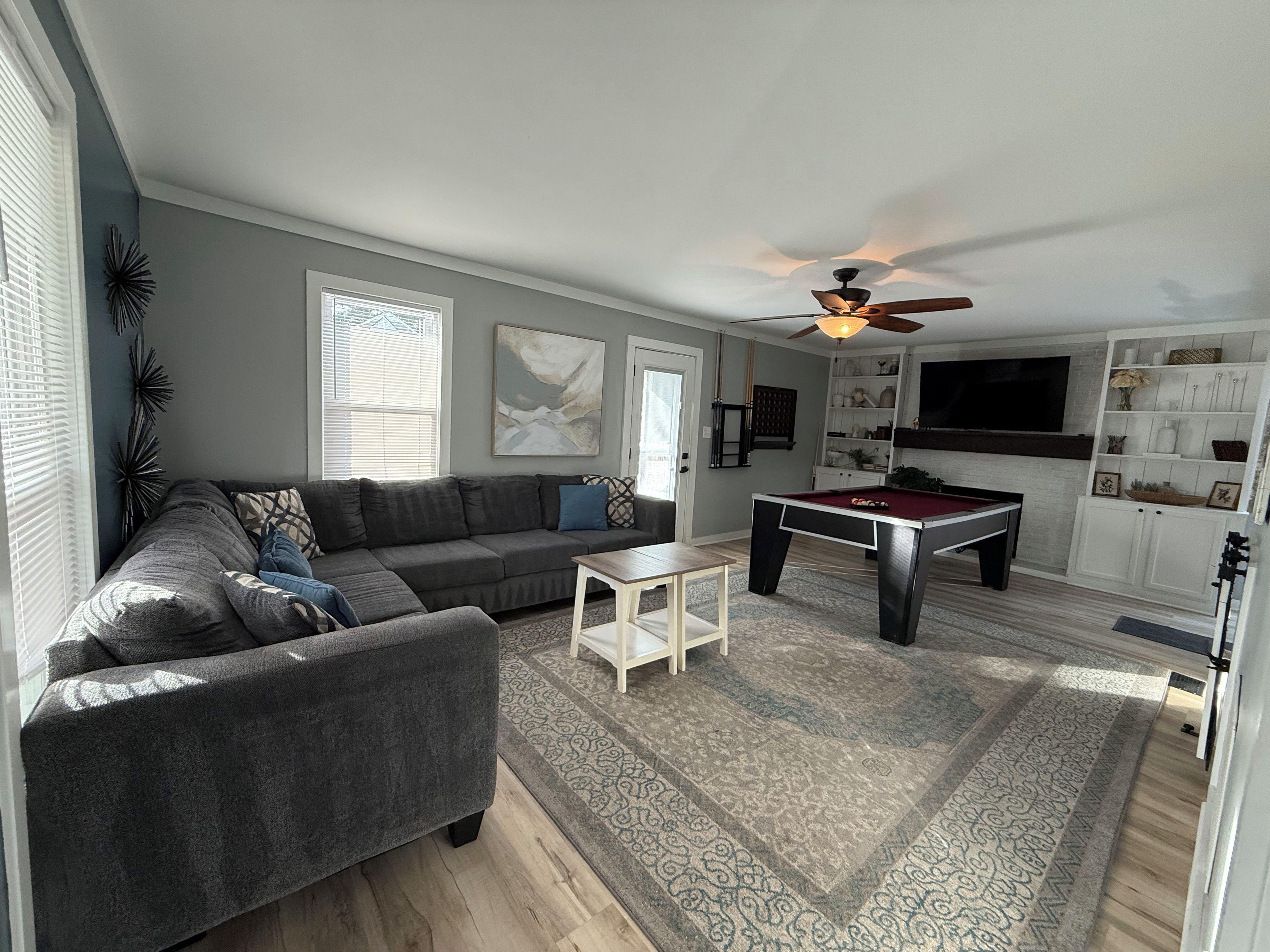 A living room with a sofa, a pool table, and a ceiling fan.