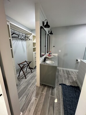 A bathroom with a wooden floor, a sink, a mirror, and a towel rack.