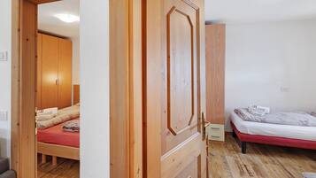 Ein Zimmer mit einem Holfischschrank, einem Bett mit roter Matratze und Holzboden.