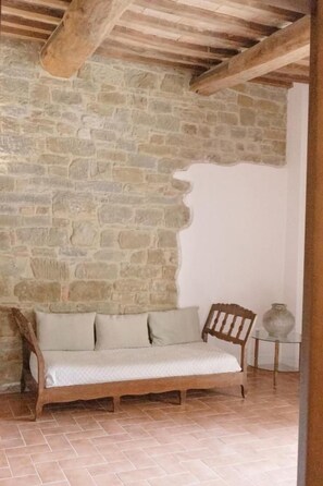 Un muro de piedra, un banco de madera y un suelo de baldosas.