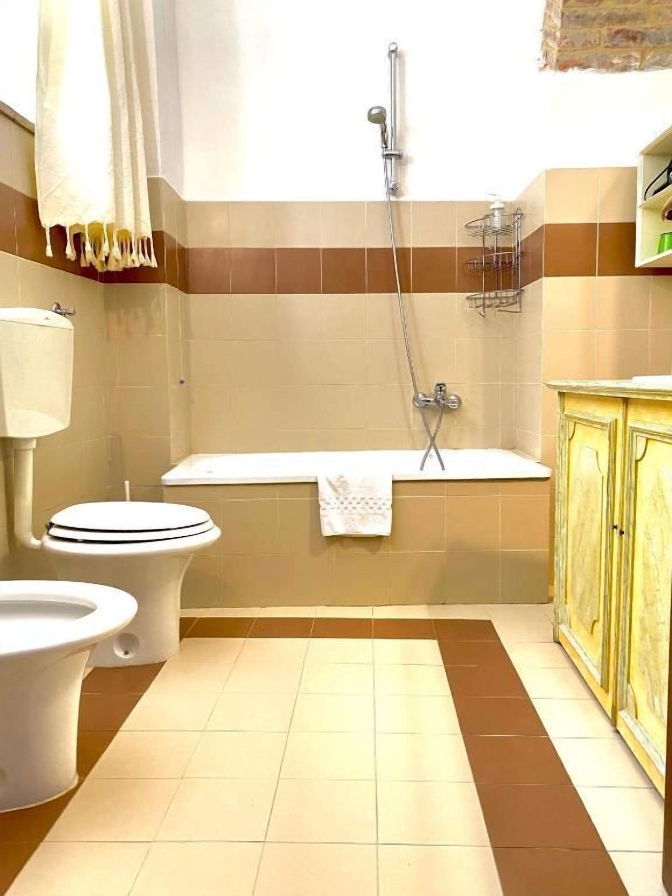Et badeværelse med toilet, badekar og bruser.