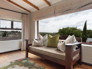 A room with a wooden bench, a view of the countryside, and a window with curtains. - Cape Goodness Guesthouse (Cape Town)