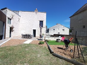 Kivestä rakennettu rakennus, jossa on patio, ulkotila istumiseen ja grilli.