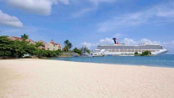 A cruise ship docked at a beach with a clear sky.