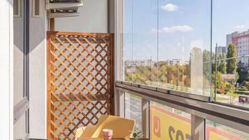 Un balcon avec une table, des chaises et un pot de fleurs.