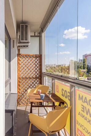 A balcony with a table, chairs, and a potted plant. - Warsaw | Międzynarodowa 31A | Spacious Apartment | Air conditioning (Warszawa)