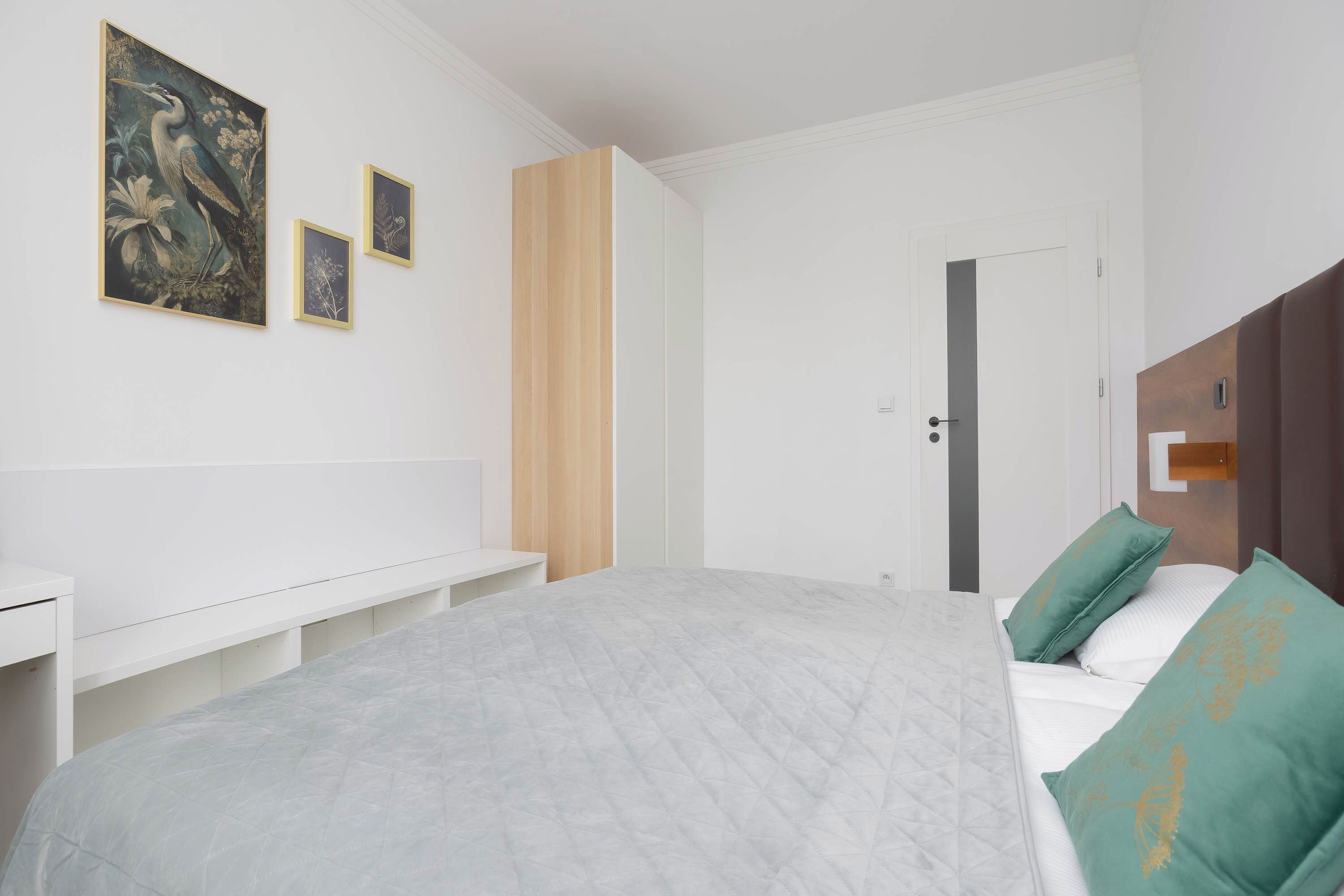 Une chambre à coucher avec un lit, un banc et trois tableaux encadrés accrochés au mur.