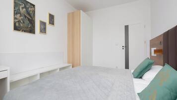 Une chambre à coucher avec un lit, un banc et trois tableaux encadrés accrochés au mur.