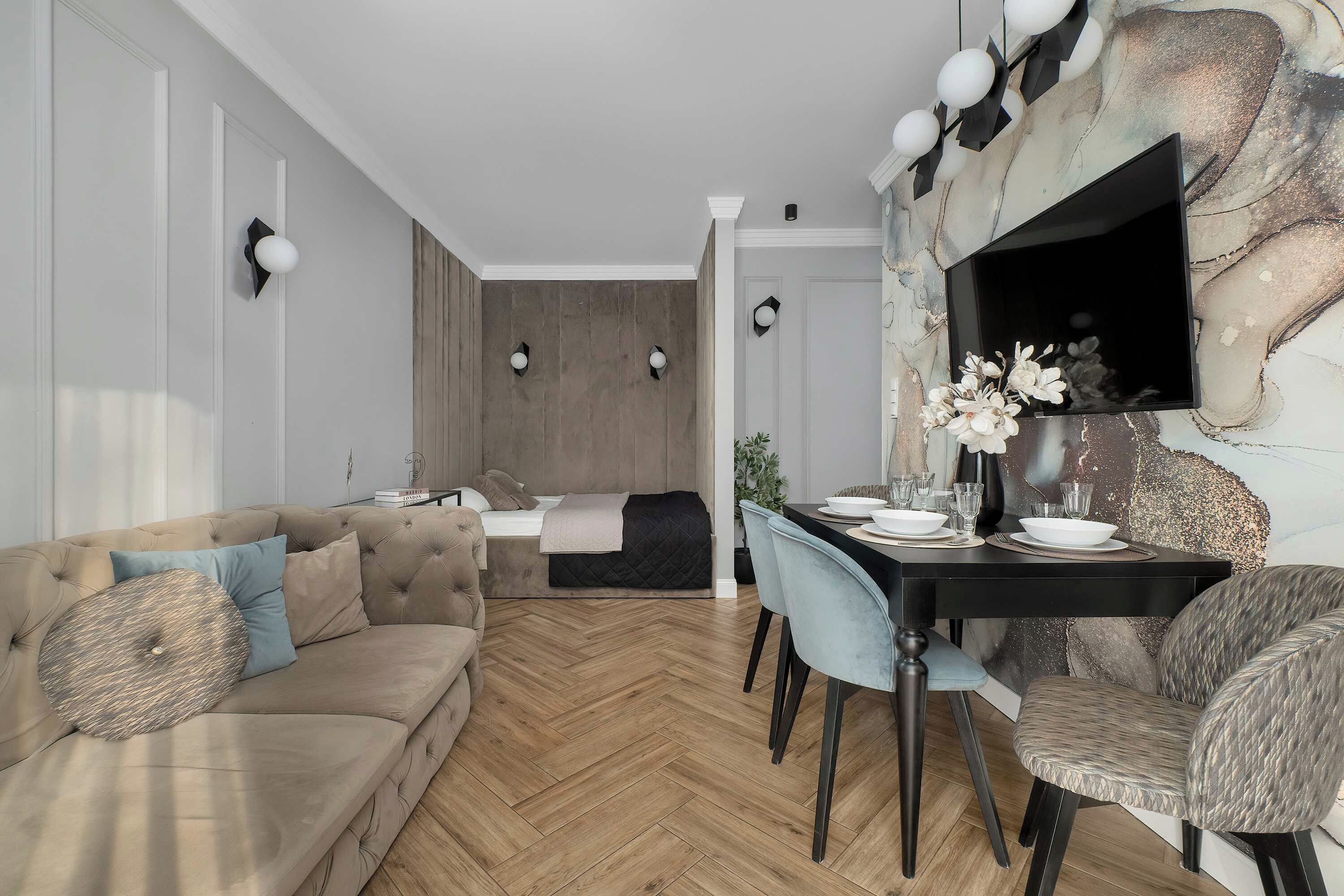 Ein modernes Wohnzimmer mit einer Couch, einem Esstisch und einem an einer strukturierten Wand befestigten Fernseher.
