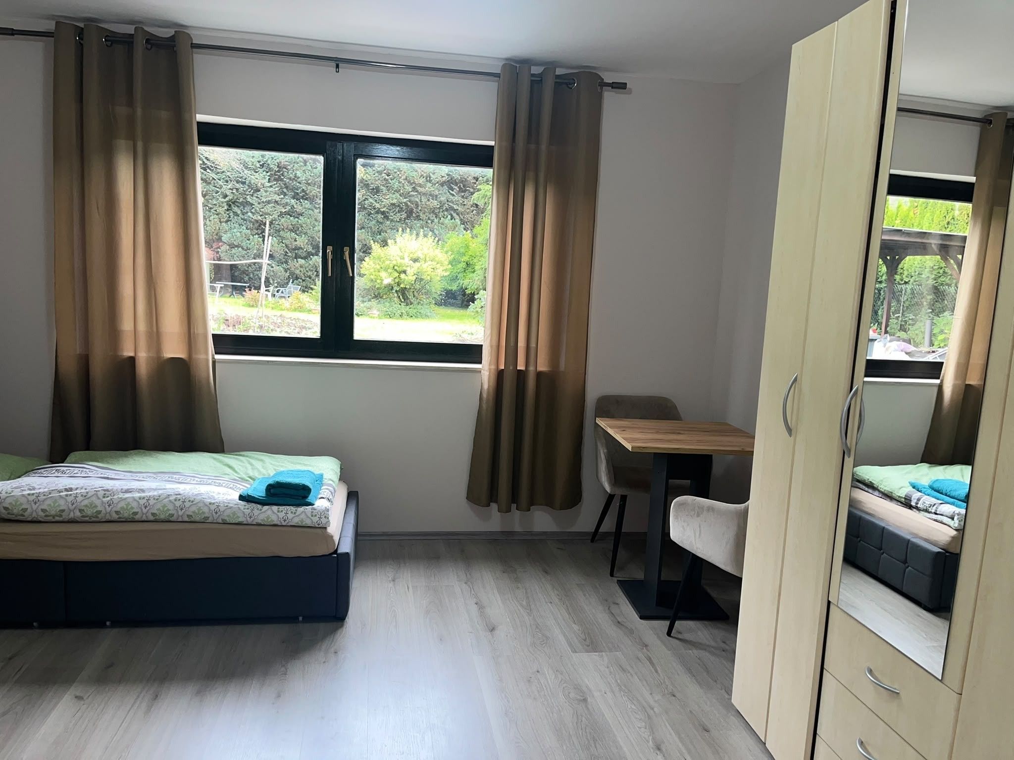 Ein Schlafzimmer mit Bett, Schreibtisch, Stuhl und Kleiderschrank.