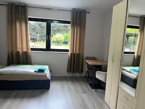A bedroom with a bed, a desk, a chair, and a wardrobe.