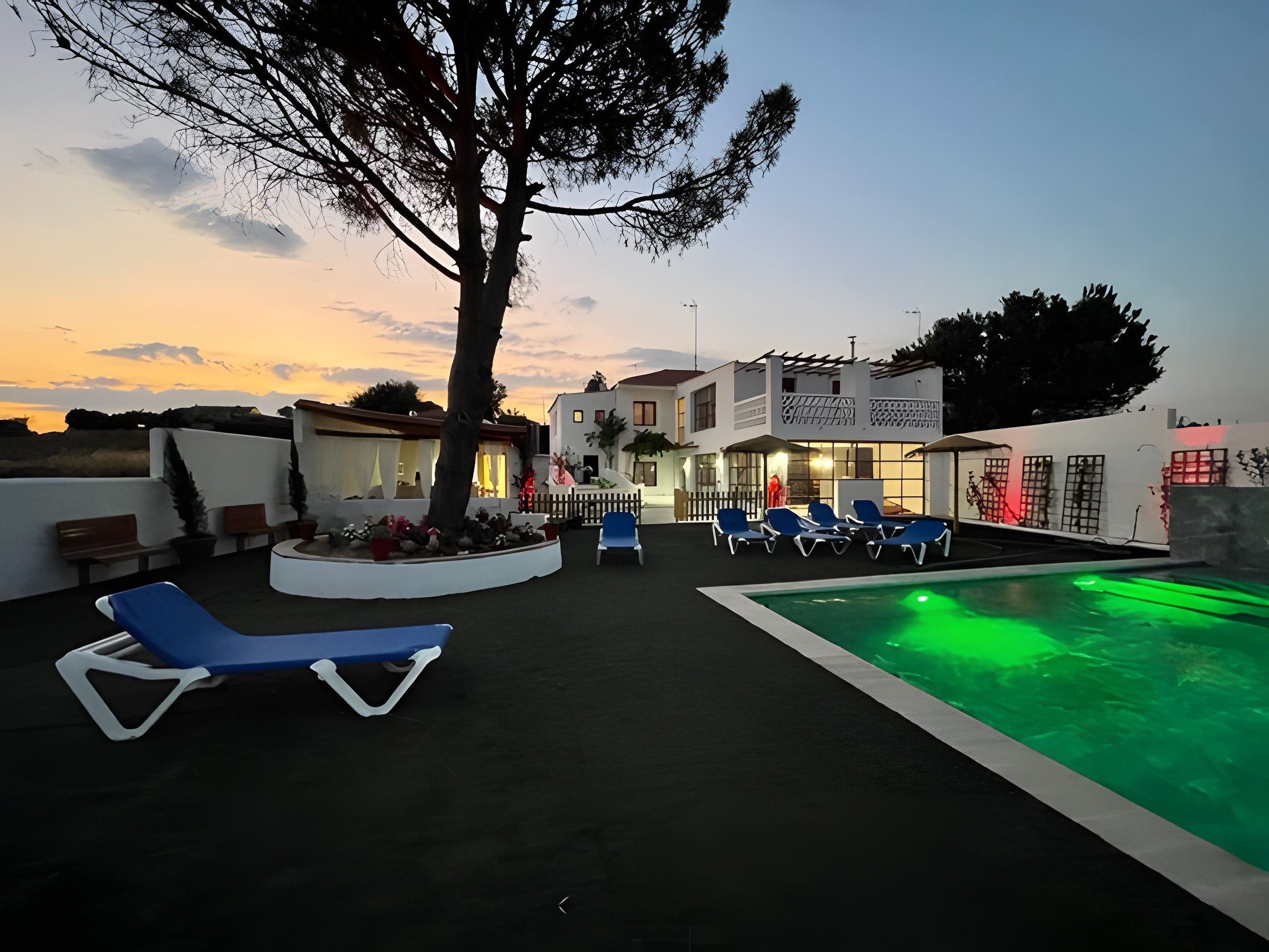 A poolside area with lounge chairs and a swimming pool at dusk.