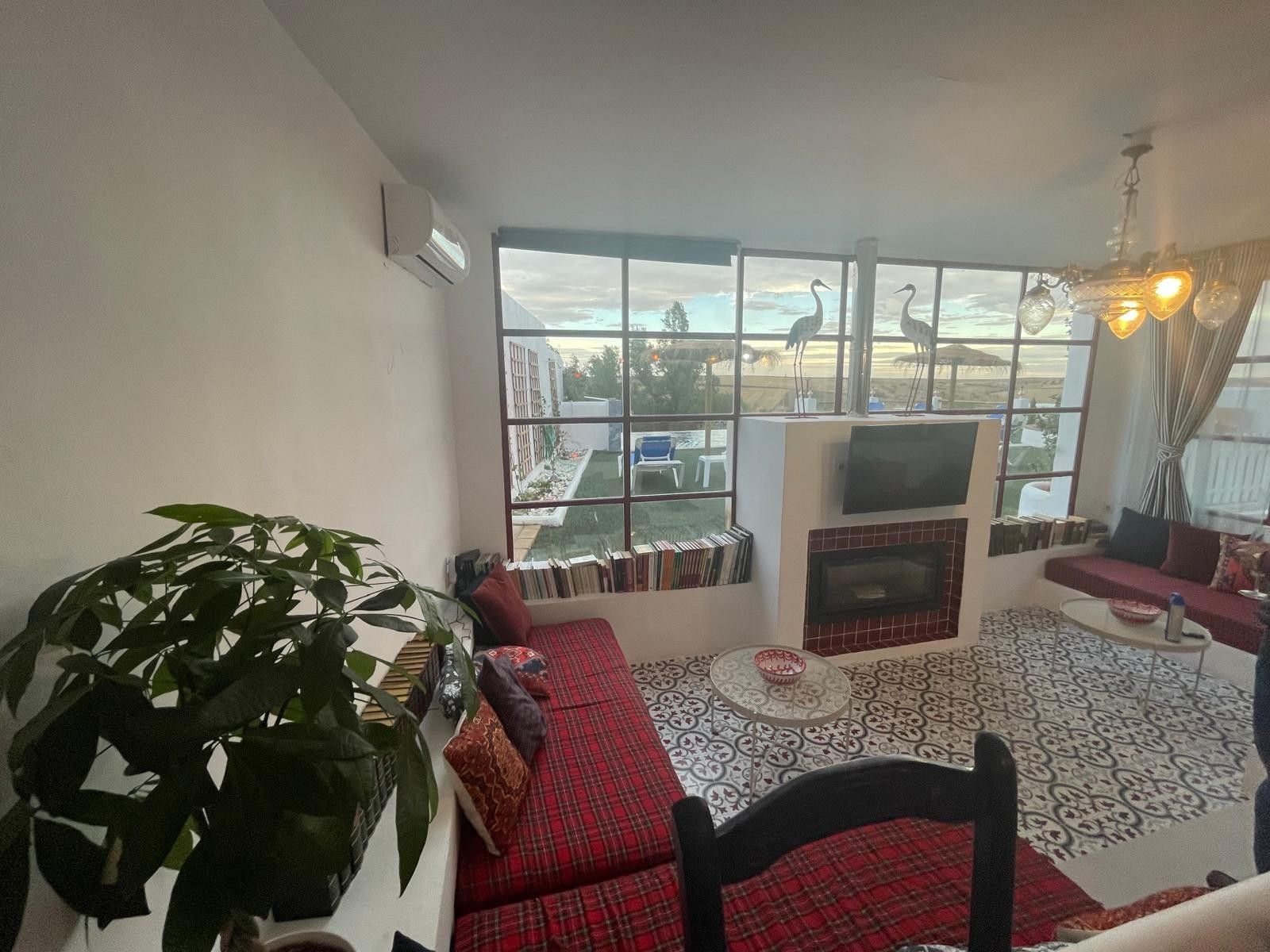 A living room with a sofa, a fireplace, a television, and a large window with a view of the outside.