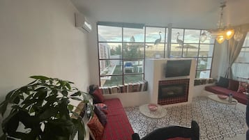 A living room with a sofa, a fireplace, a television, and a large window with a view of the outside.