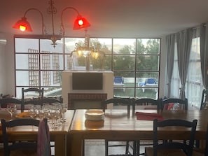 Ruokailutila, jossa on takka, suuret ikkunat ja näkymä ulos.