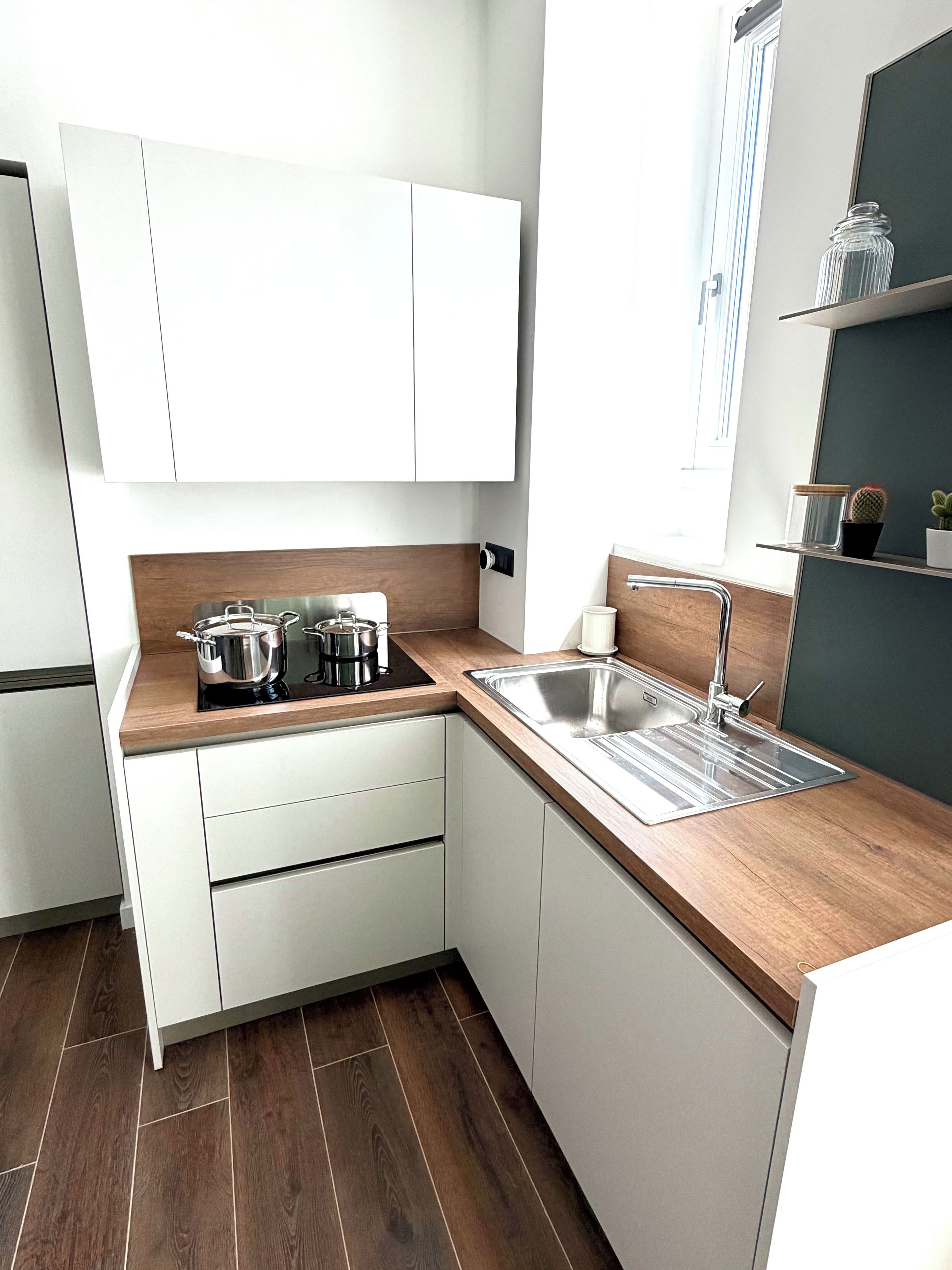 A modern kitchen with white cabinets, a wooden countertop, stainless steel appliances, and a built-in sink.