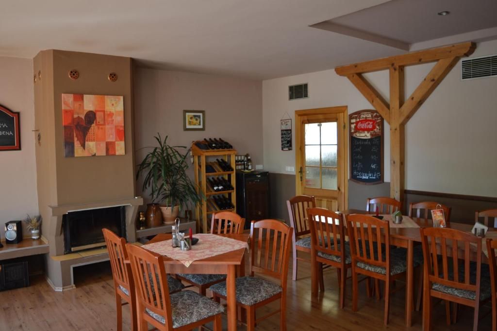 A dining area with wooden tables and chairs, a fireplace, a wine rack, and a chalkboard menu.