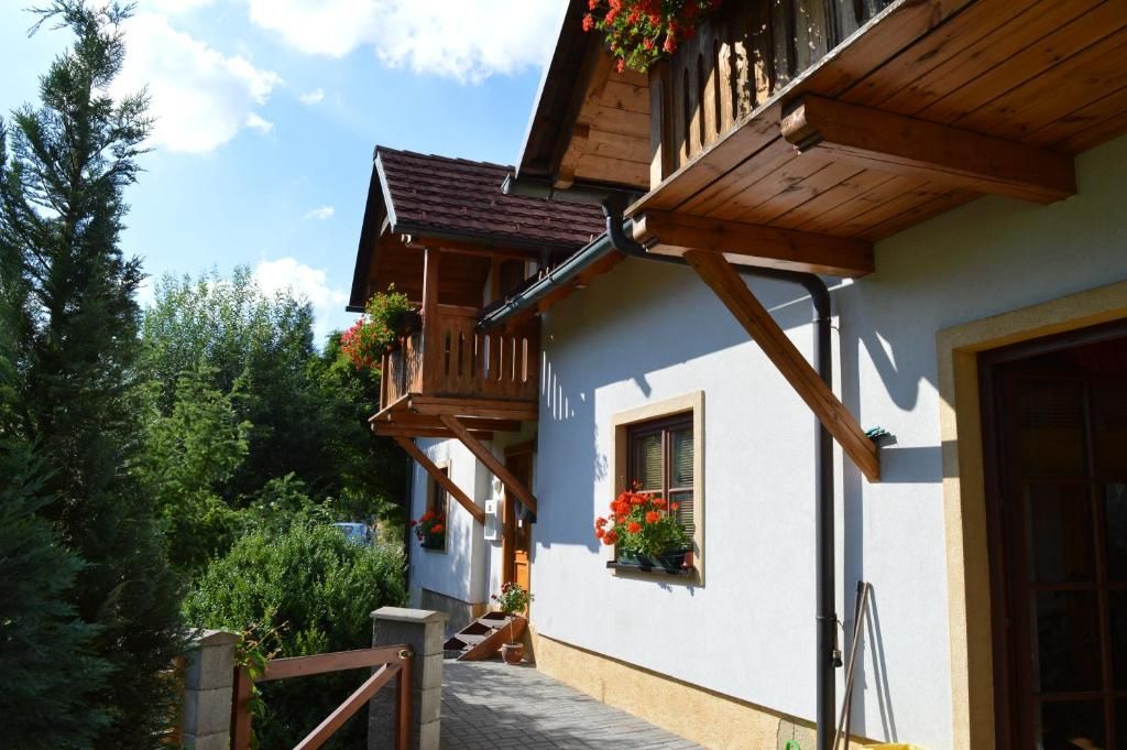 A traditional chalet with wooden balconies, a stone staircase, and flower boxes.