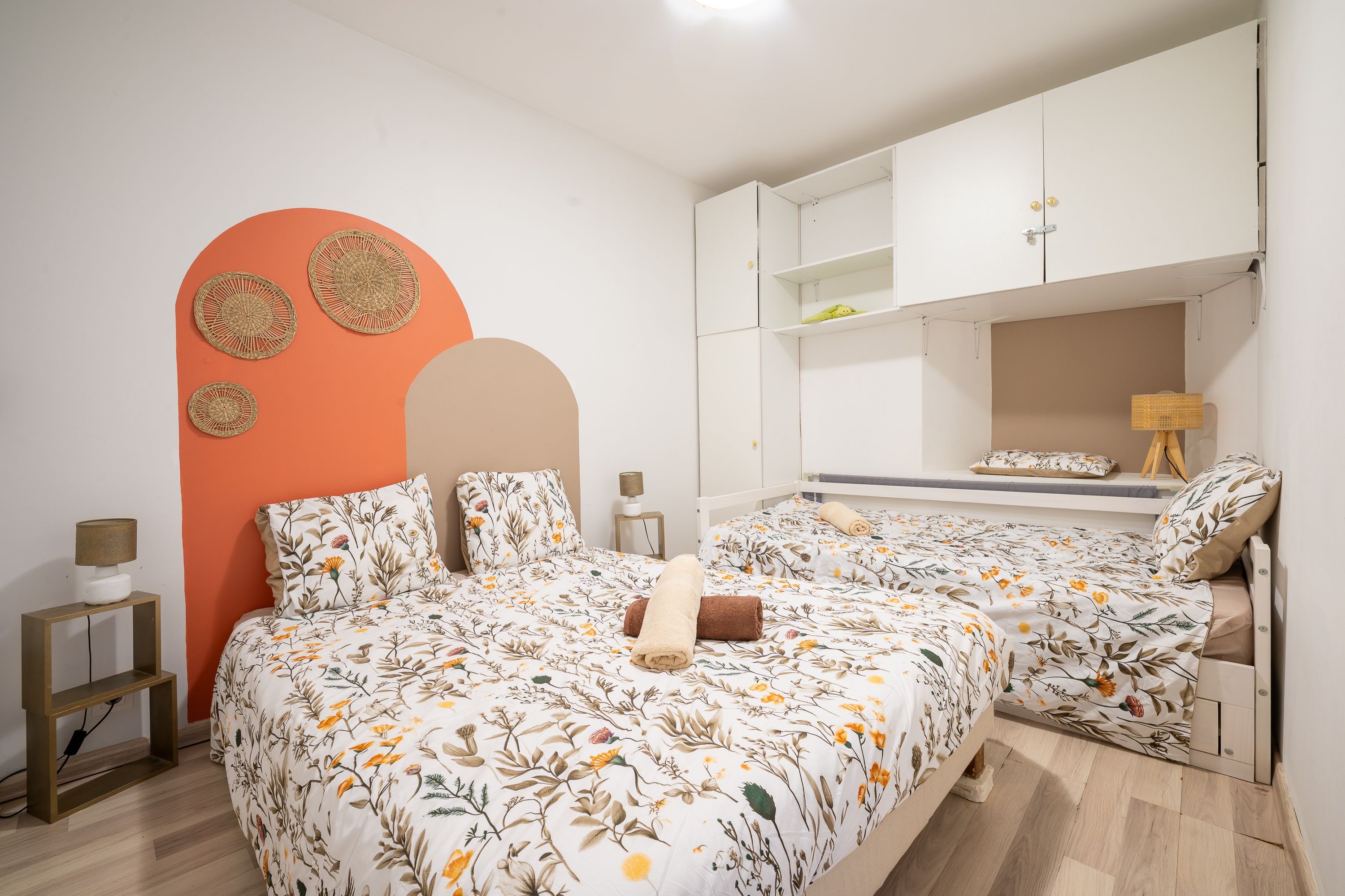 A bedroom with a bed, a nightstand, a lamp, and a wardrobe.